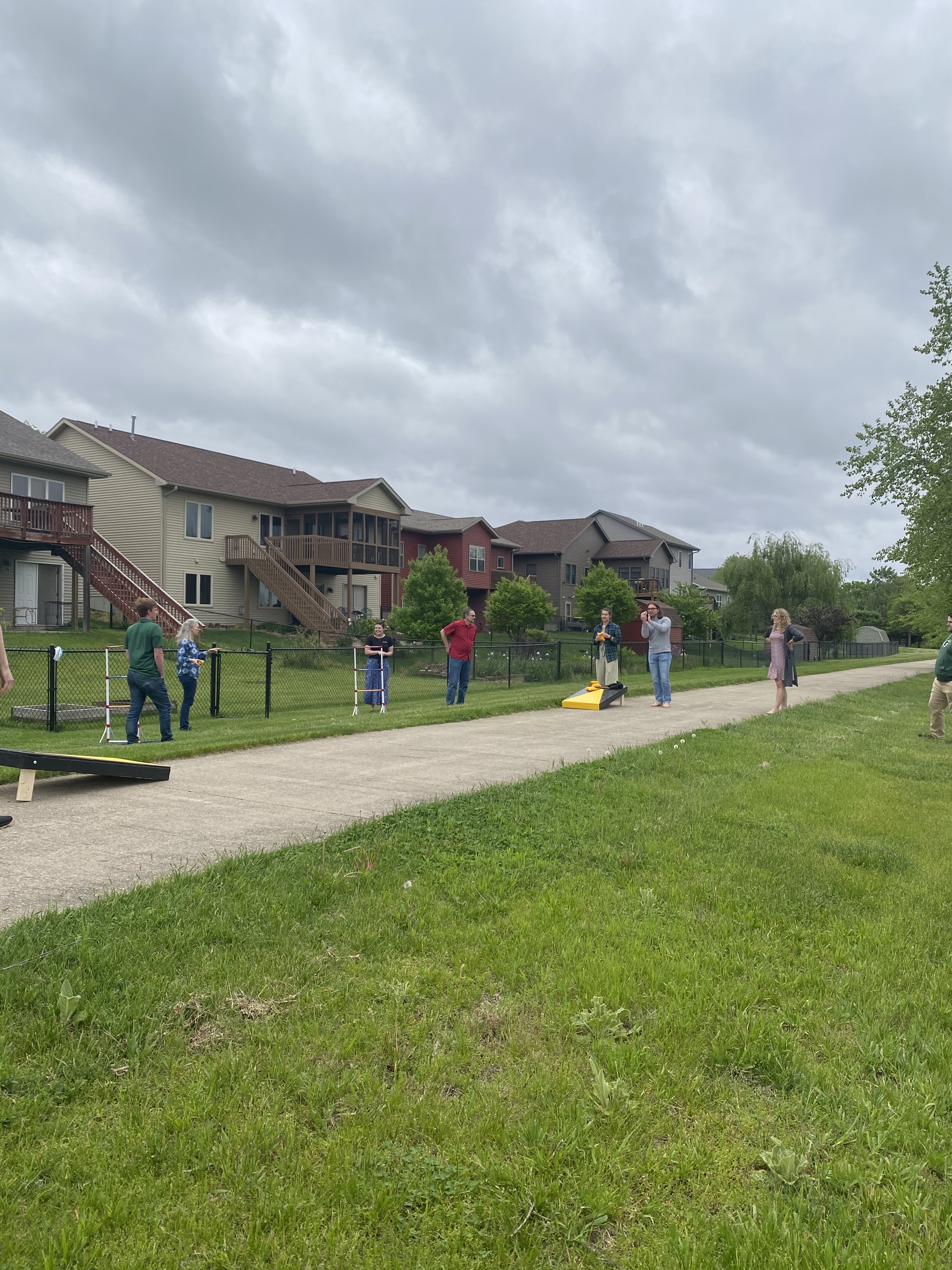 Cole group members and loved ones playing corn hole and setting up yard golf outside on a cloudy day