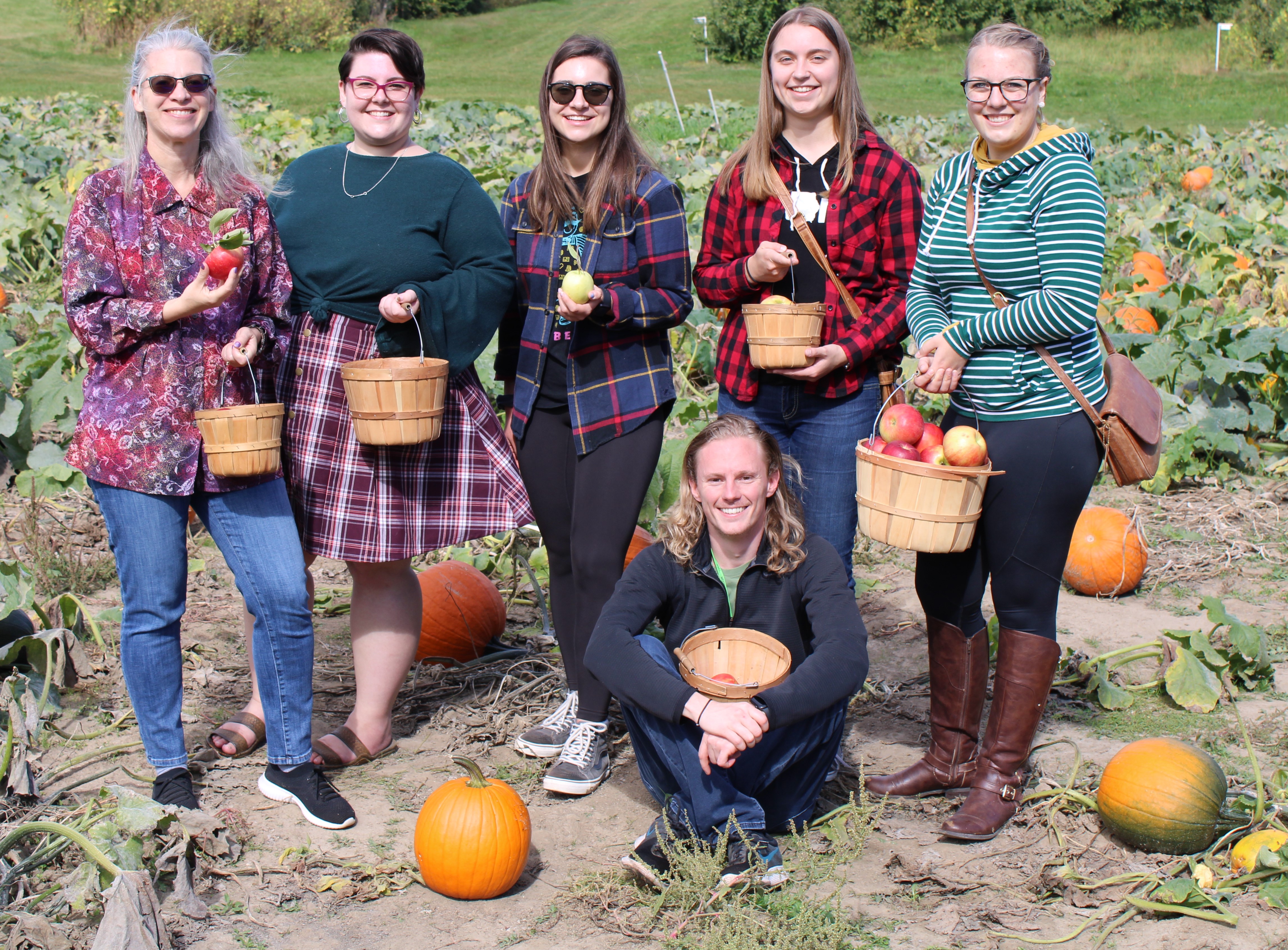 Cole group showing off their perfectly picked apples while standing in the pumpkin patch