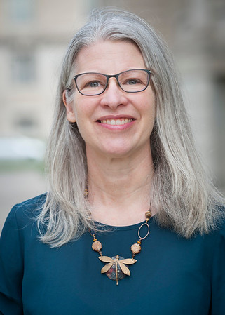 Renée Cole smiling for her award photo wearing a blue top with a dragonfly statement necklace.