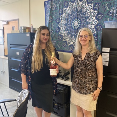 Katie and Renée standing with a bottle of champagne celebrating a successful new doctorate degree