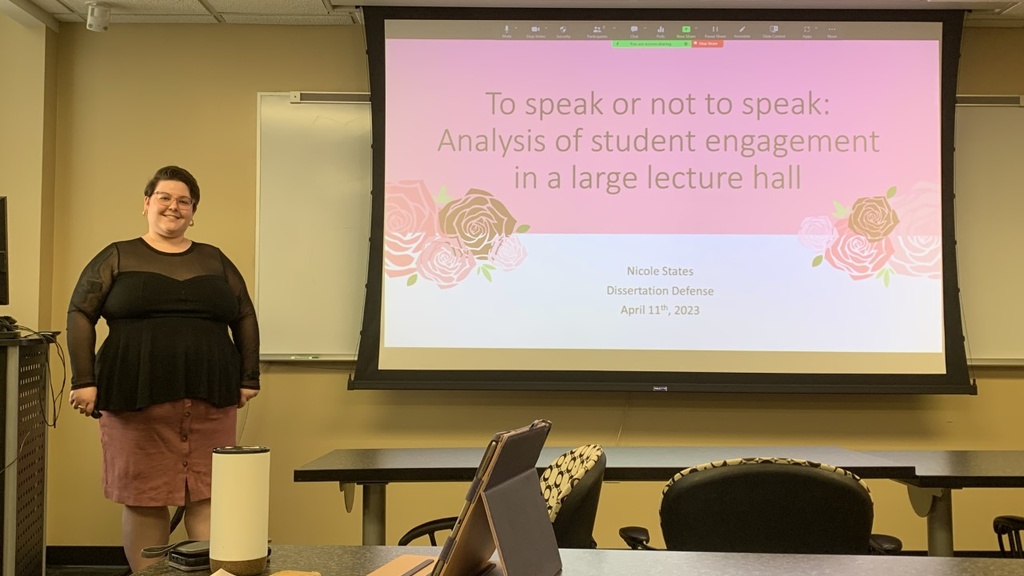 Nicole standing by her dissertation defense slides
