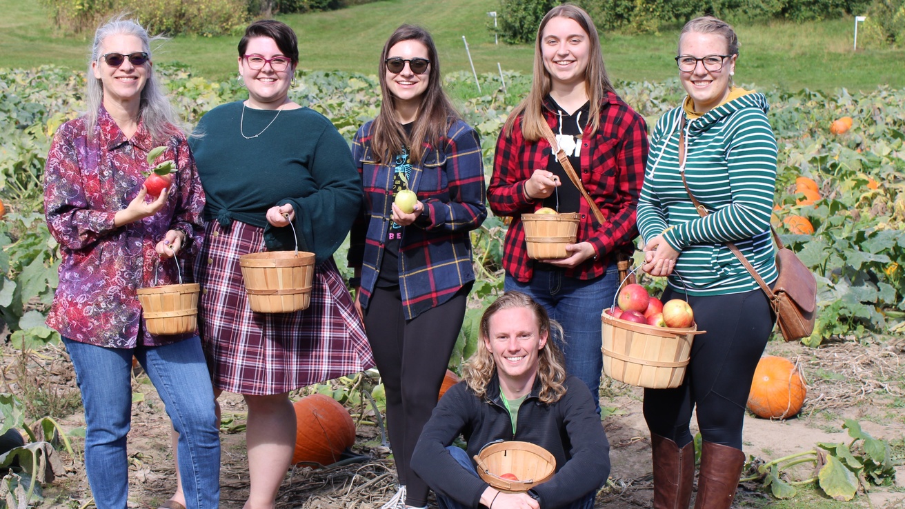 Cole group showing off their perfectly picked apples while standing in the pumpkin patch