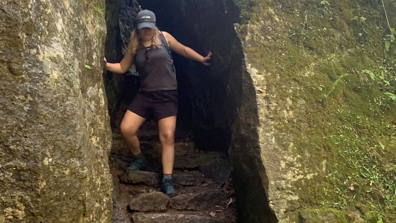 Hannah going through a cave opening